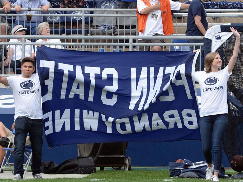 two students carrying a flag in the stadium for All-U Day